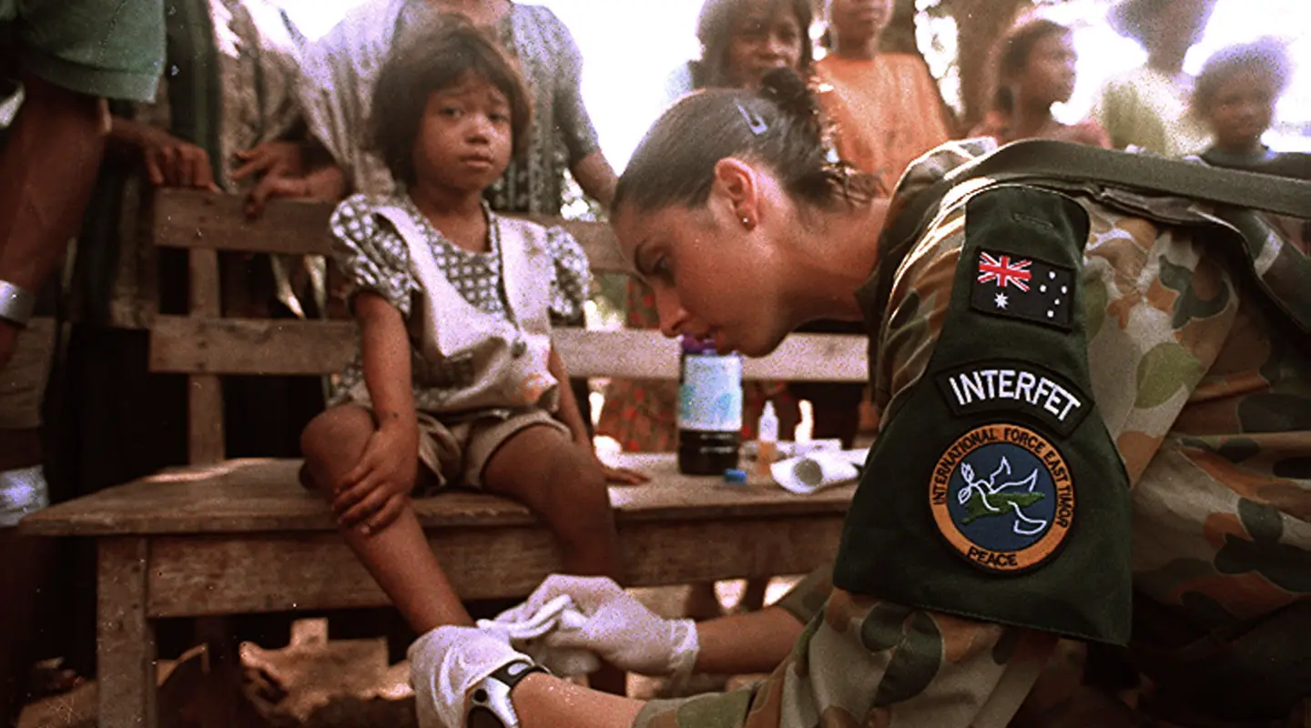 Private Tammy Smithson provides medical assistance to a child in Suai's marketplace