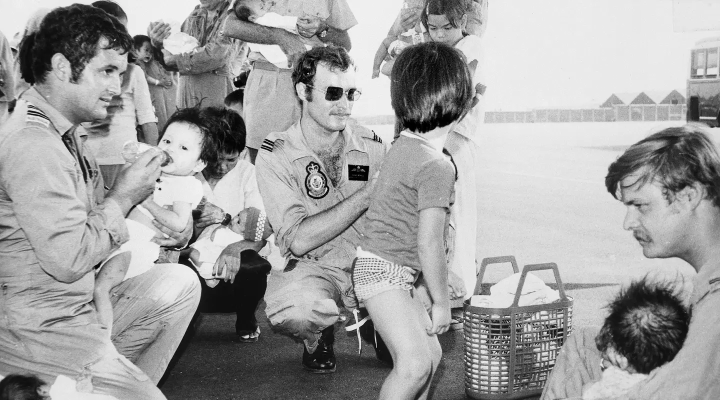 Three RAAF members bottle feed Vietnamese babies at Tan Son Nhut airfield