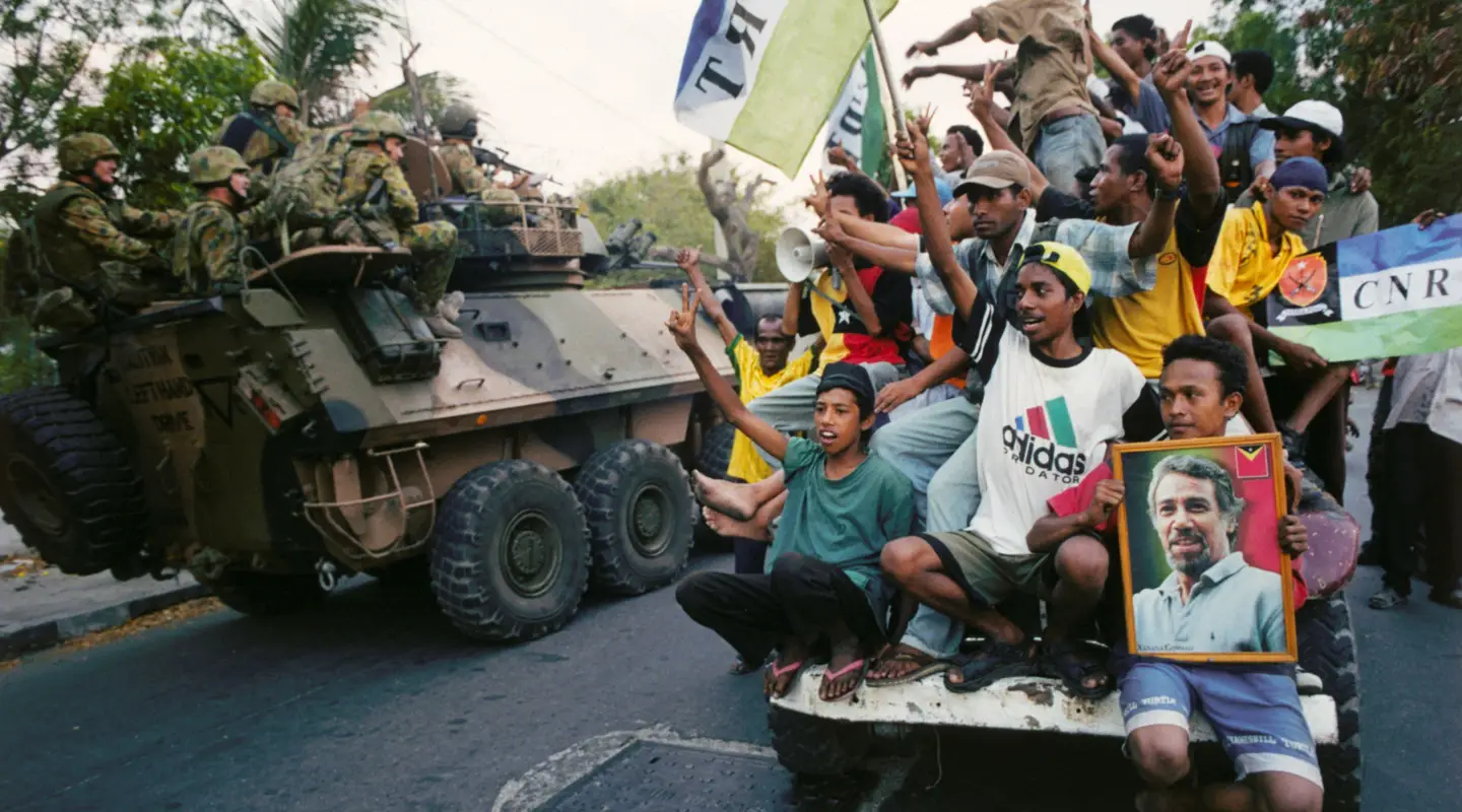 Australian troops serving in INTERFET pass a group of East Timorese locals celebrating independence.
