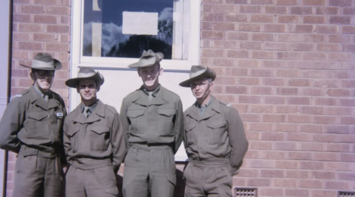 Group portrait or four National Servicemen recruits and room-mates in front of the new three-storied brick accommodation blocks at Kapooka in which they lived while undergoing basic training.