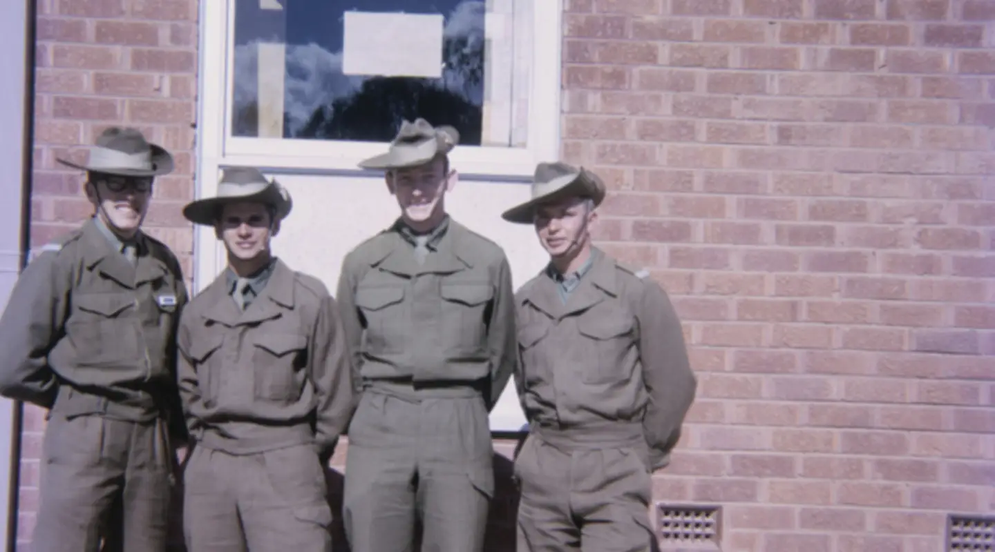 Group portrait or four National Servicemen recruits and room-mates in front of the new three-storied brick accommodation blocks at Kapooka in which they lived while undergoing basic training.