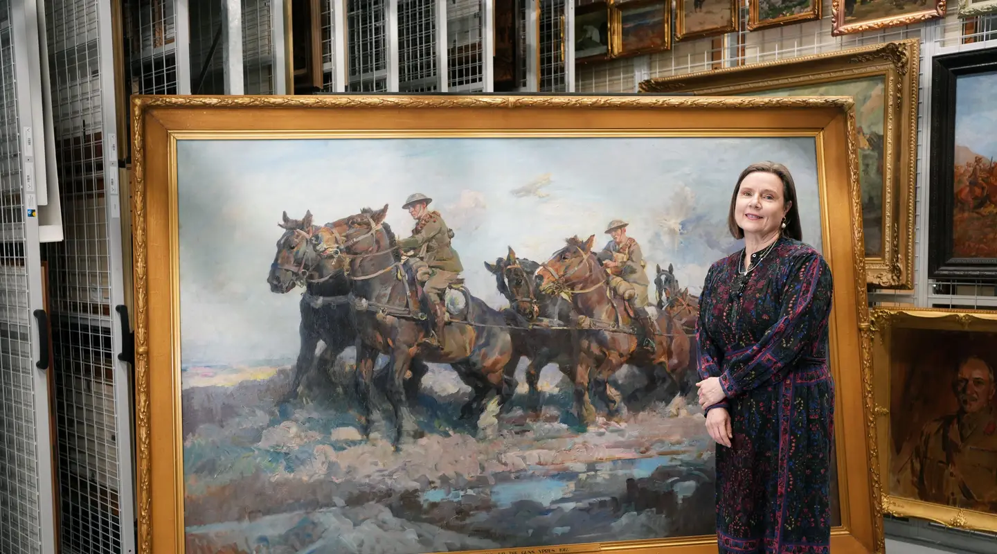 Dr Lara Nicholls stand with the large scale artwork Bringing up the guns by Septimus Power. 