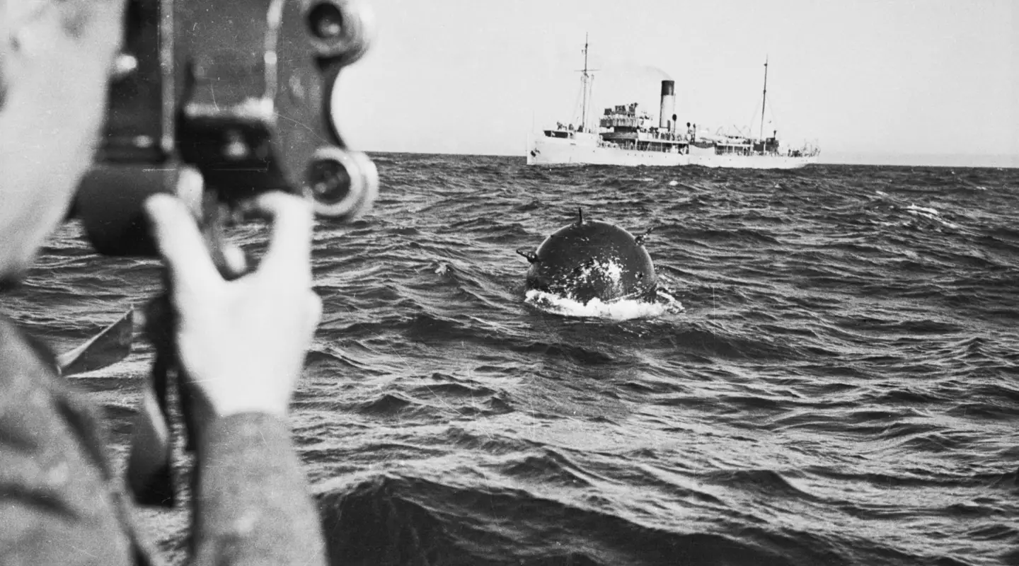 On board the minesweeper HMAS Orara, filming a German mine which has been swept from Bass Strait, 1940