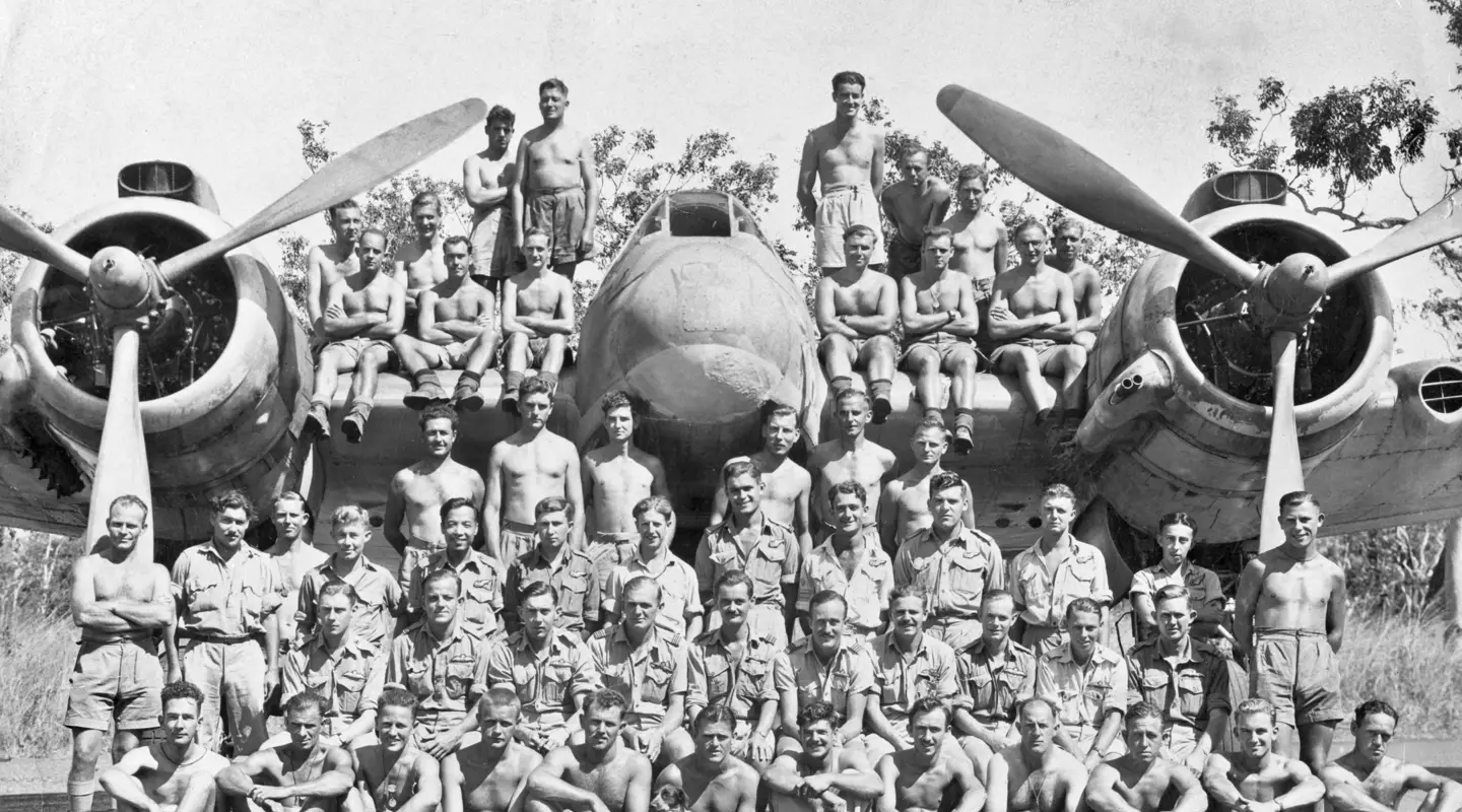 Group portrait of members of No 31 Squadron RAAF assembled on and in front of one of the unit's Bristol Beaufighter aircraft.