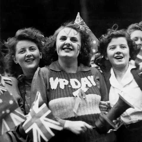  Three female work mates from the Kodak factory at Abbotsford, Melbourne celebrate the end of the Second World War. In the centre, Miss Lois Martin, wears a VP DAY sweater vest.