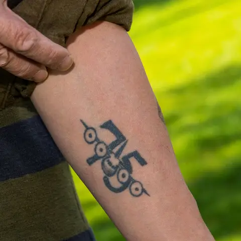 Forearm tattoo of the C-130 Hercules with '75' behind it
