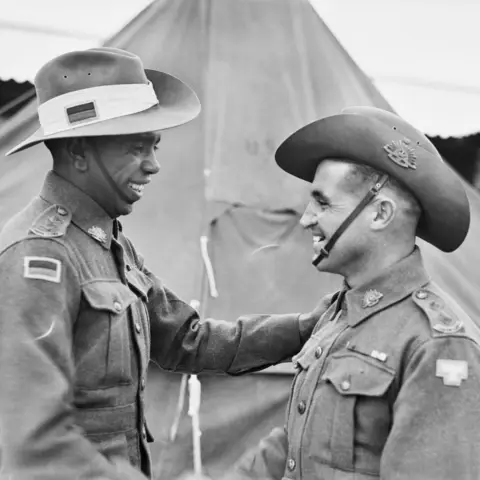 Reg Saunders and Tom Derrick shake hands after graduating from the Officer Cadets Training Unit