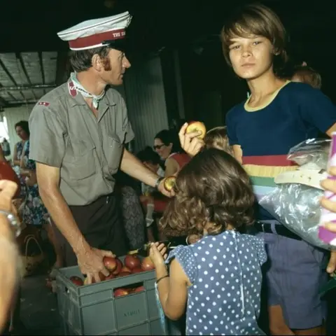 A salvation army volunteer distributes food in Darwin following Cyclone Tracy in 1974.  Photo courtesy National Archives of Australia.