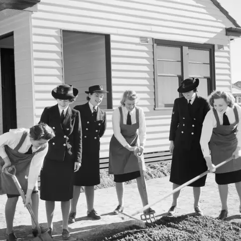 WRANS gardening outside their cottage at HMAS Harman.
