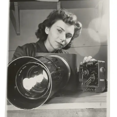 A WAAAF photographer checking an aerial camera prior to final assembly