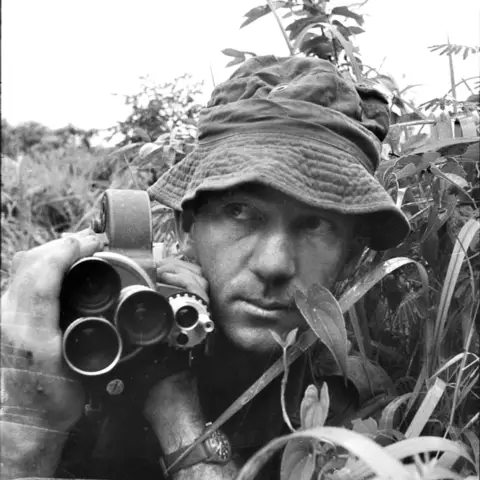 Sergeant Mike Coleridge holding a Bell & Howell 16mm movie camera
