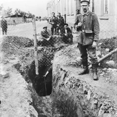 German guards inspect an exposed section of an escape tunnel leading from the Holzminden Prisoner of War (POW) Camp