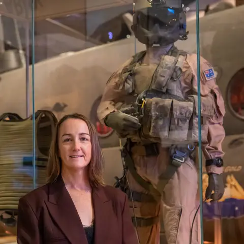 Naomi Shephard standing in front of her uniform display in the Afghanistan gallery