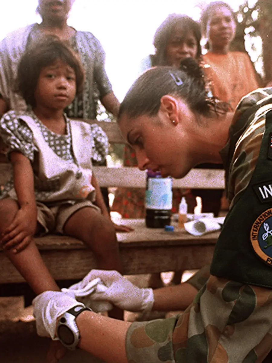 Private Tammy Smithson provides medical assistance to a child in Suai's marketplace