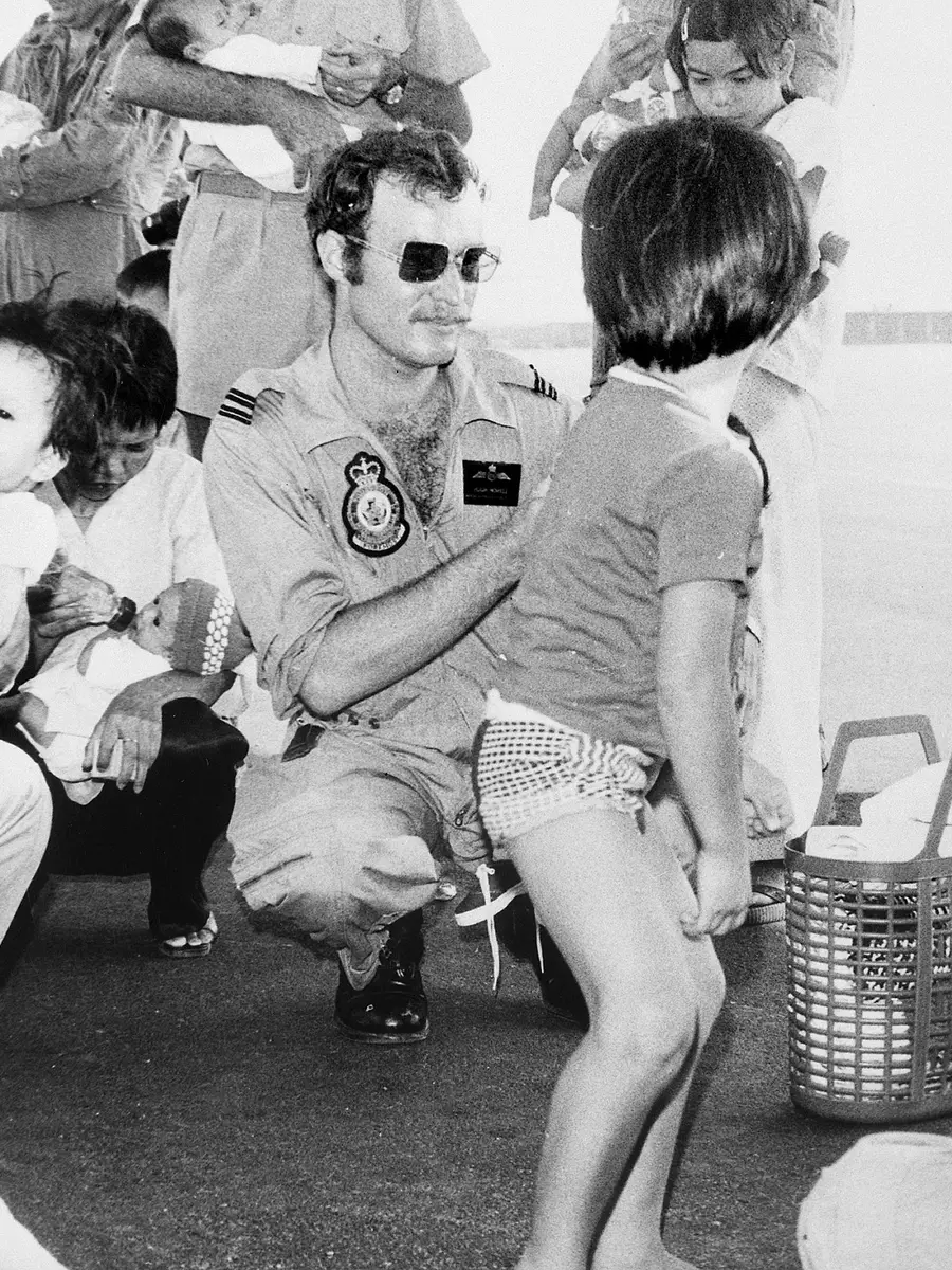 Three RAAF members bottle feed Vietnamese babies at Tan Son Nhut airfield