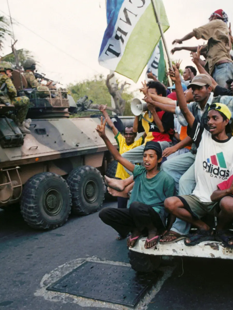 Australian troops serving in INTERFET pass a group of East Timorese locals celebrating independence.