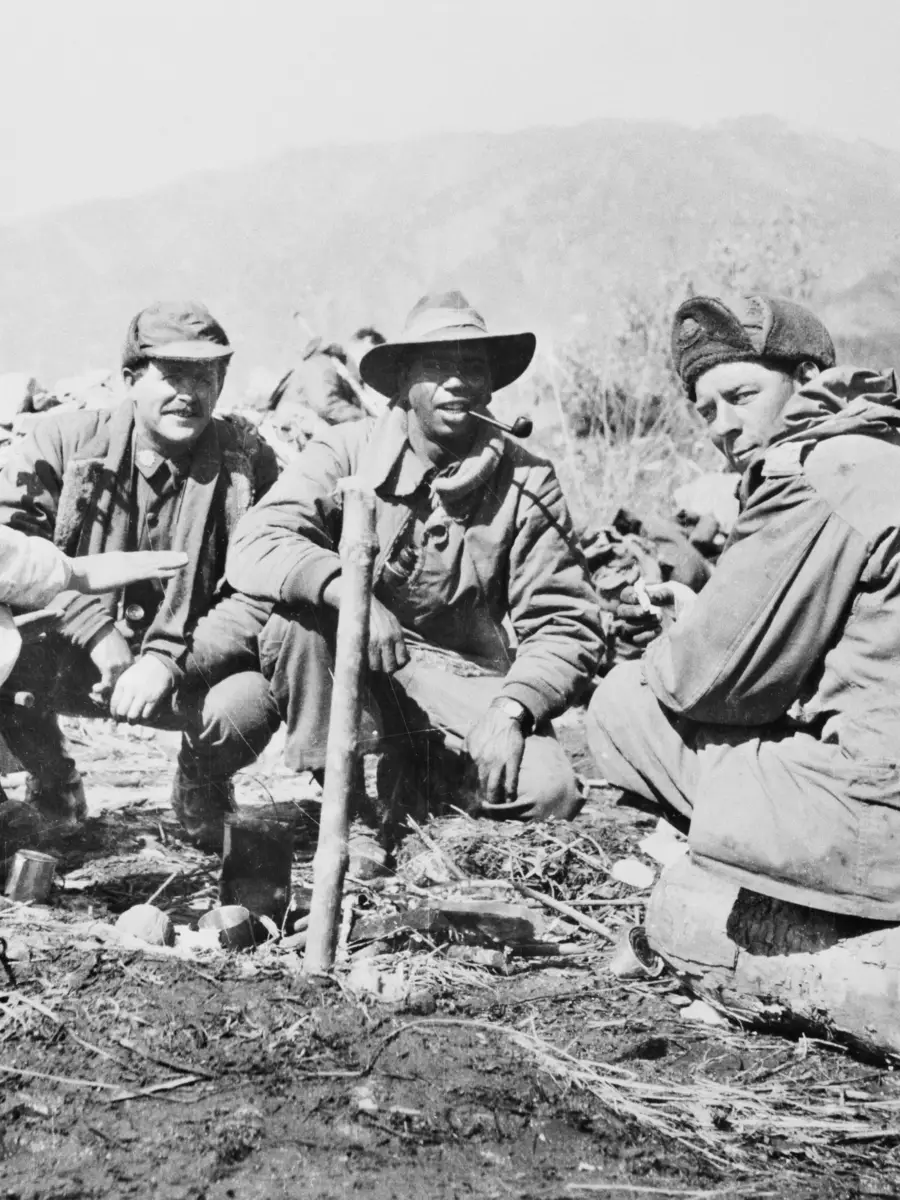 Three members of the 3rd Battalion, The Royal Australian Regiment (3RAR), confer with a North Korean interpreter (left) who is serving with the battalion. Saunders is second from the right, smoking a pipe.