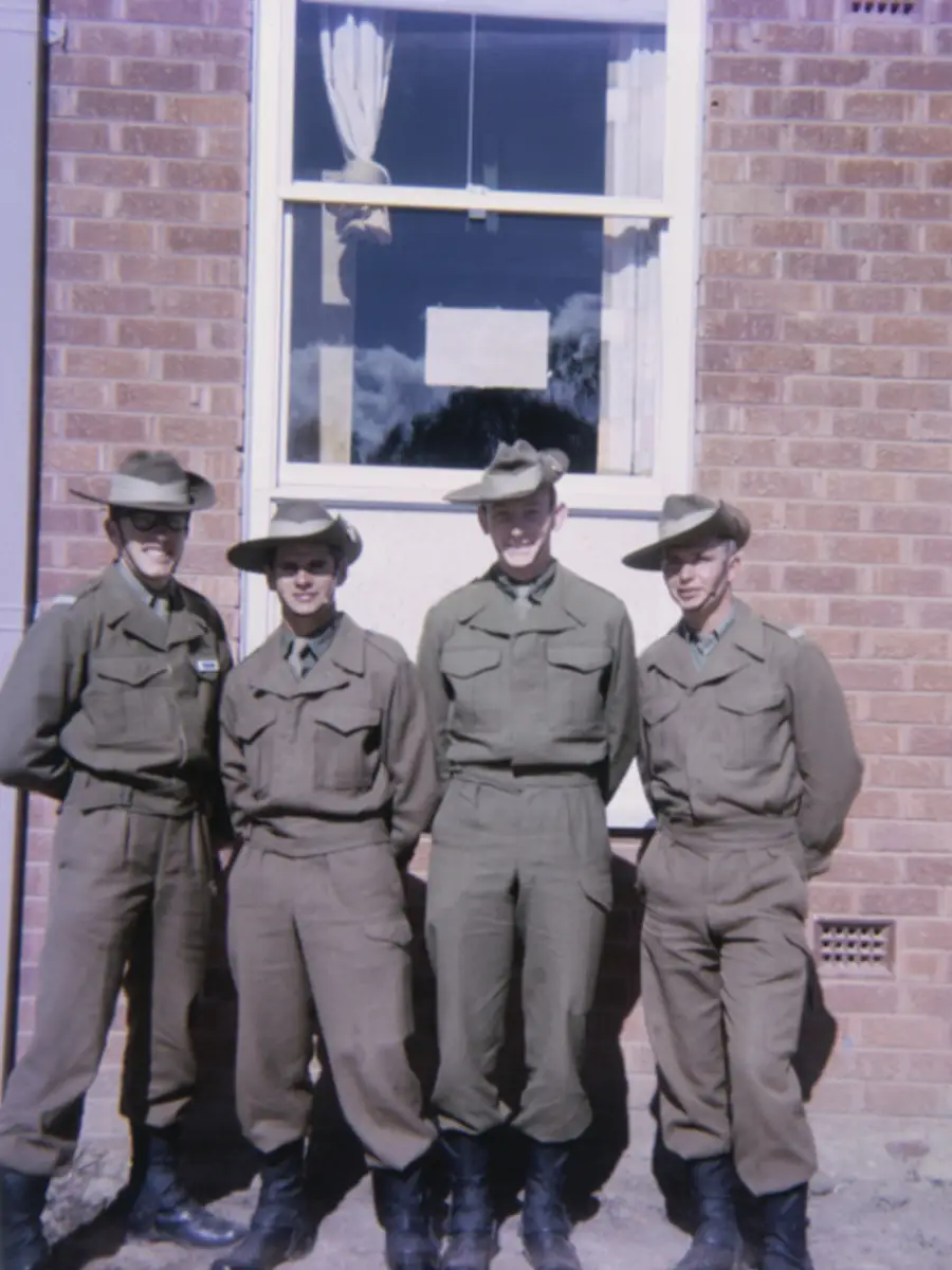 Group portrait or four National Servicemen recruits and room-mates in front of the new three-storied brick accommodation blocks at Kapooka in which they lived while undergoing basic training.