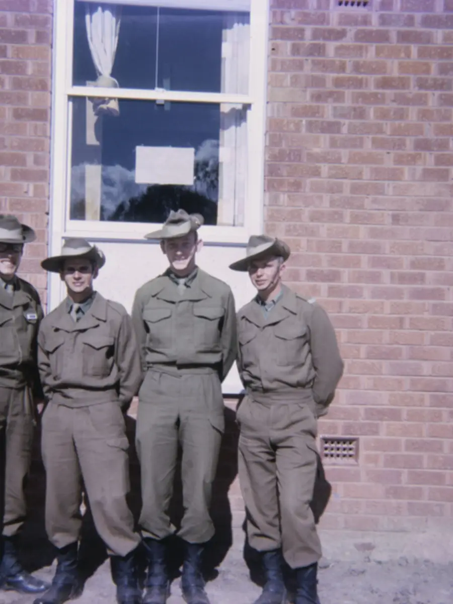 Group portrait or four National Servicemen recruits and room-mates in front of the new three-storied brick accommodation blocks at Kapooka in which they lived while undergoing basic training.