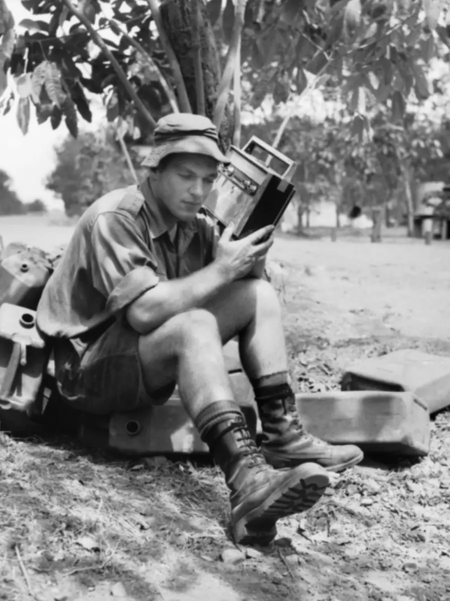 Holding a radio close to his ear as he listens to news from Australia is Private Robert Foot, 1RAR.