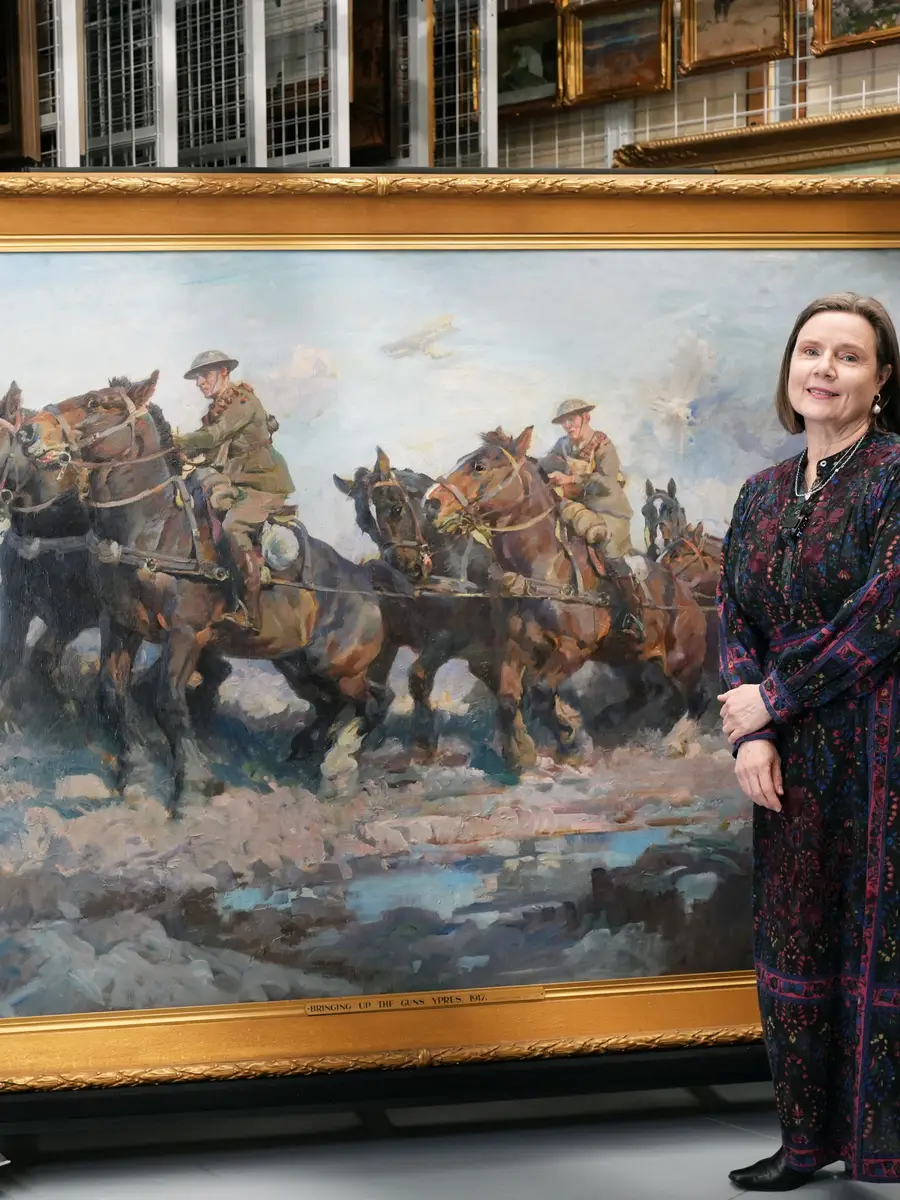 Dr Lara Nicholls stand with the large scale artwork Bringing up the guns by Septimus Power. 