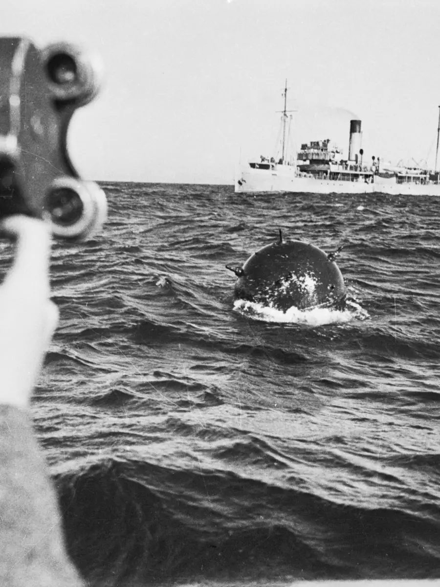 On board the minesweeper HMAS Orara, filming a German mine which has been swept from Bass Strait, 1940