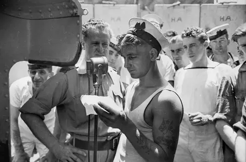 Lawrence H. Cecil of the ABC, recording messages home on board HMAS Perth, 1941. 