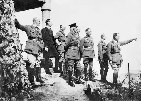 A group of uniformed men look off into the distance with Sir Philip Chetwode pointing in one direction.
