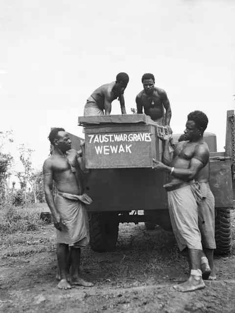 Men with the Australian New Guinea Administrative Unit unload caskets for reburial at Wewak war cemetery