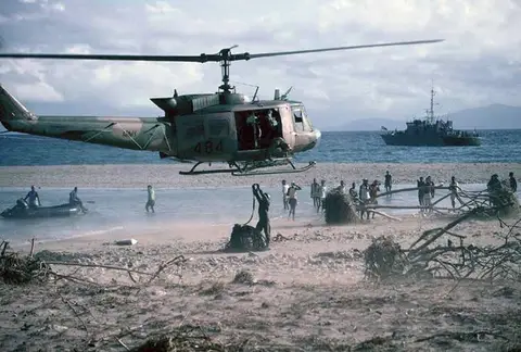  An Iroquois from 171st Command and Liaison Squadron delivering relief supplies to a remote northern island of Vanuatu, January 1992. The Vanuatu police patrol boat was provided by Australia.  Photo: Paul Copeland.