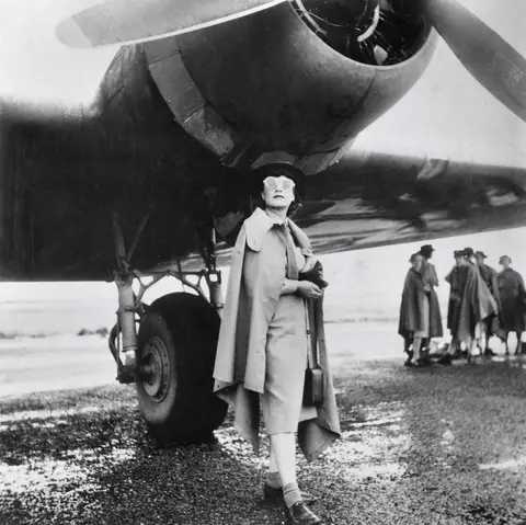 Iris Dexter standing under the starboard engine of a Doughlas C-47 aircraft. Photograph by Barbara Isaacson.