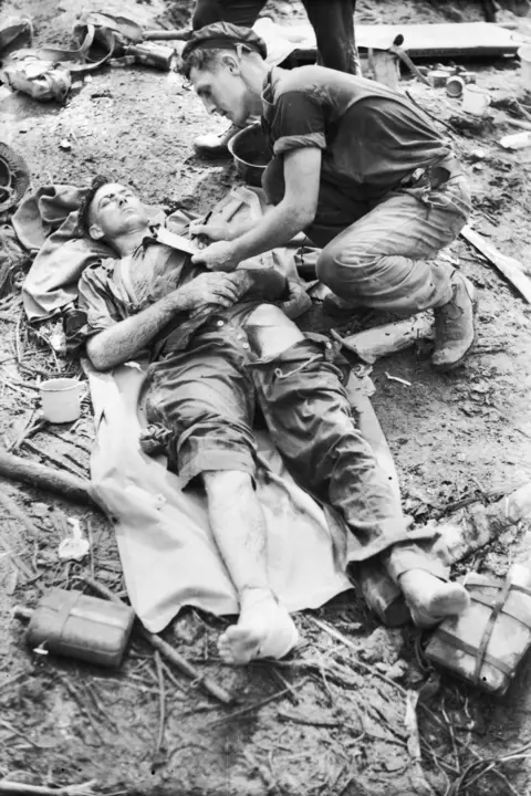 Private J. J. Ryan (left) wounded on Little George Hill, receiving medical attention