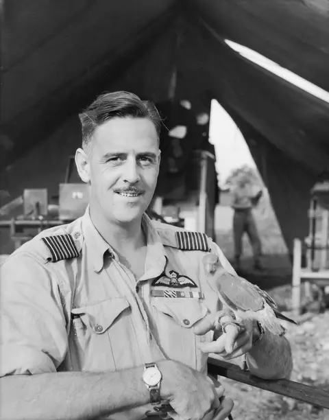 Caldwell with a pet parrot outside his command tent on Morotai