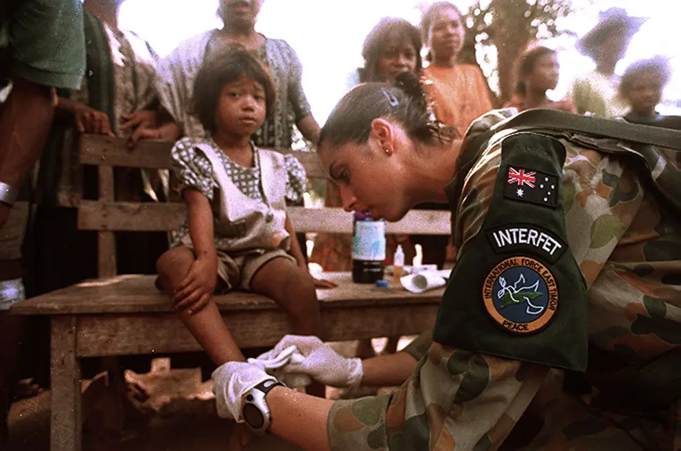 Private Tammy Smithson provides medical assistance to a child in Suai's marketplace