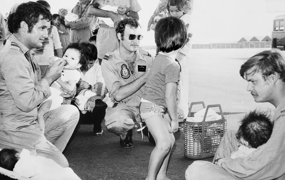 Three RAAF members bottle feed Vietnamese babies at Tan Son Nhut airfield
