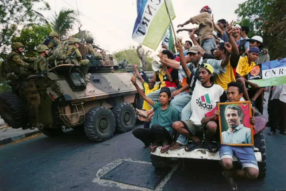 Australian troops serving in INTERFET pass a group of East Timorese locals celebrating independence.