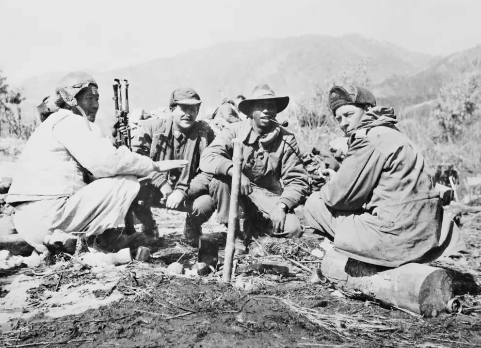 Three members of the 3rd Battalion, The Royal Australian Regiment (3RAR), confer with a North Korean interpreter (left) who is serving with the battalion. Saunders is second from the right, smoking a pipe.