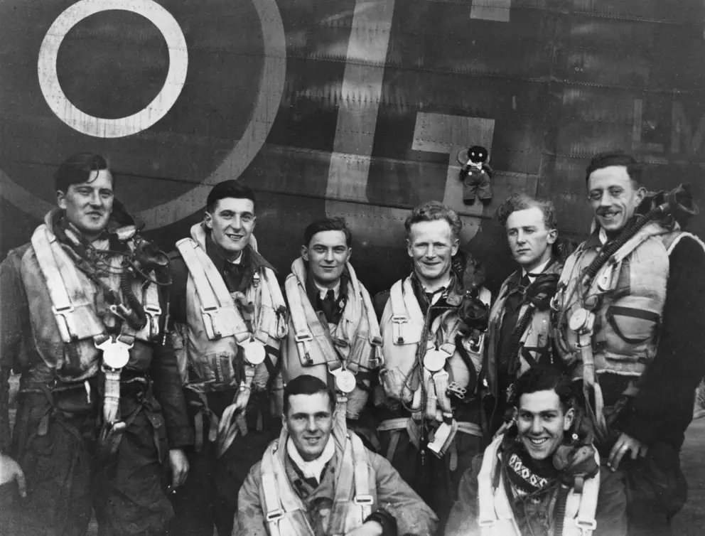 A group of men pose for a photo. Six men stand behind and two men are crouched in front.