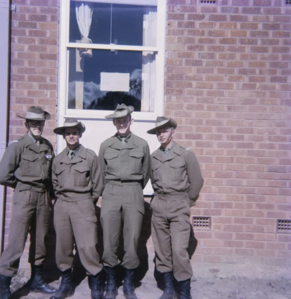 Group portrait or four National Servicemen recruits and room-mates in front of the new three-storied brick accommodation blocks at Kapooka in which they lived while undergoing basic training.