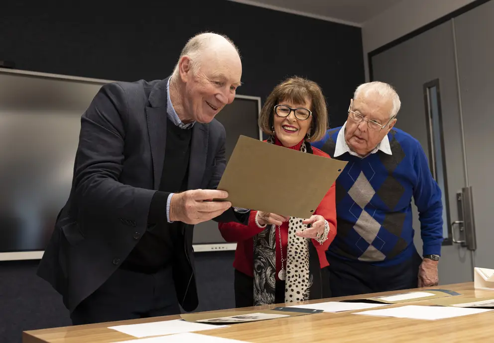 Robert Swannell, Jane Menck and Jim Menck viewing First World War photographs of Major Blair Swannell