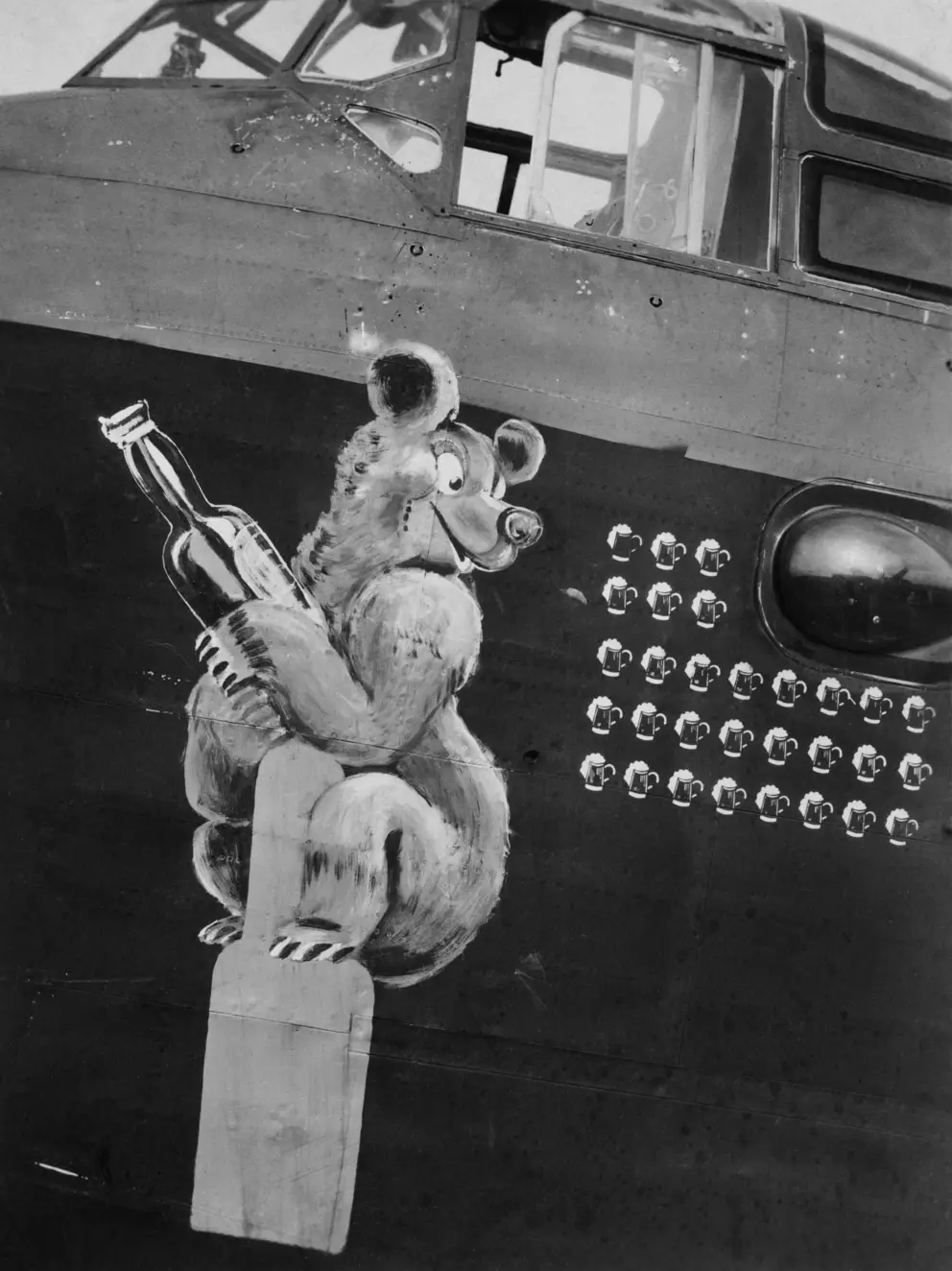 LAKENHEATH, SUFFOLK, ENGLAND, C. 1943. AN EXAMPLE OF NOSE ART ON B FOR BEER, STIRLING BOMBER EX-B, LJ-514 WHOSE CREW INCLUDED AUSTRALIANS FROM NO. 199 SQUADRON RAF. THE ILLUSTRATION DEPICTS A BEAR CLUTCHING A BEER BOTTLE, THE SORTIES ARE LOGGED ON THE SIDE BY PICTURES OF BEER MUGS. AWM P01238.001