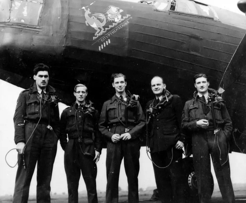 RAF Station Leconfield, England. c. 1943. The crew of Wellington LN289 standing under the nose of their aircraft which has the nose art painting of a kangaroo smacking Adolf Hitler up a flight of stairs with his tail and the words "git up them stairs". The five bombs painted under the caricature indicated the aircraft has flown five operational missions. AWM P03179.001