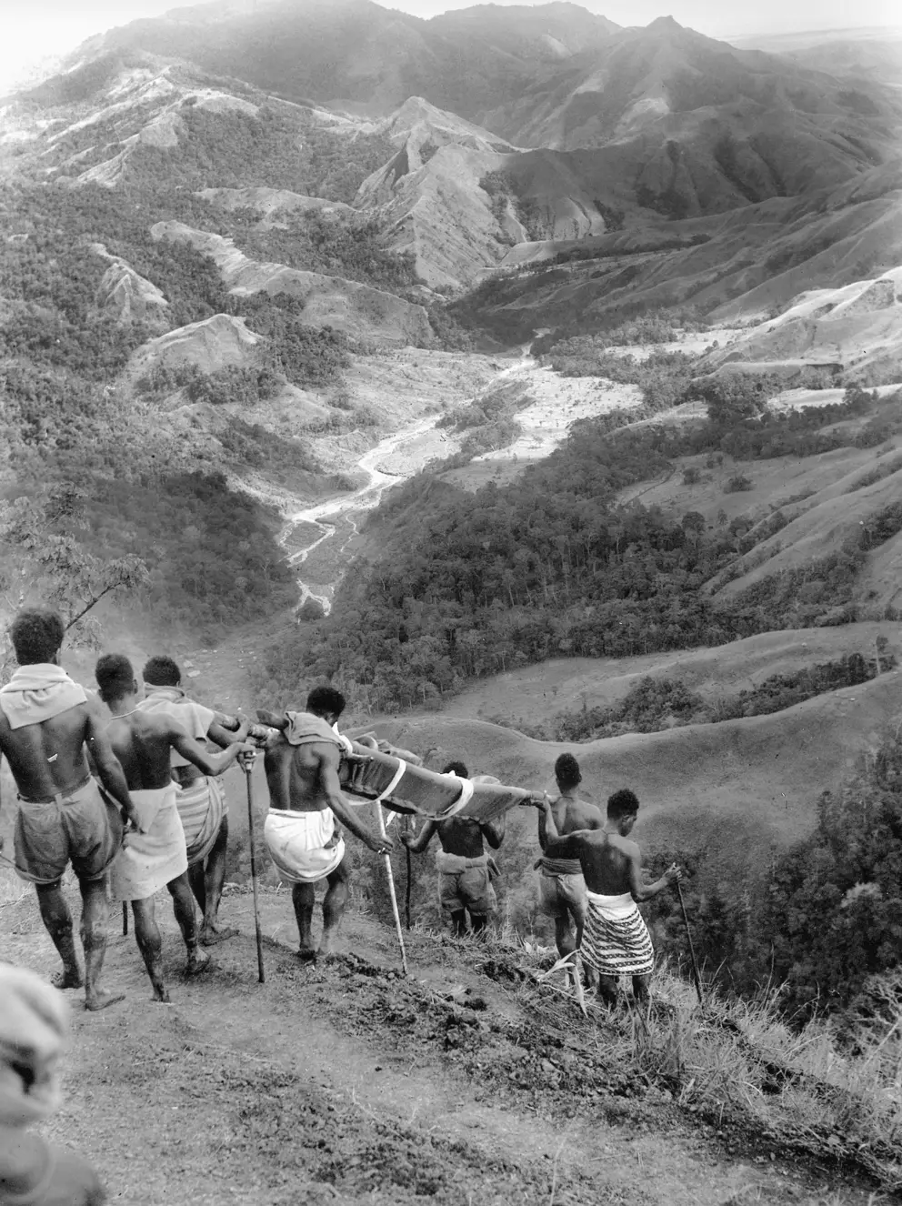 Native bearers carrying a stretcher case down from Shaggy Ridge