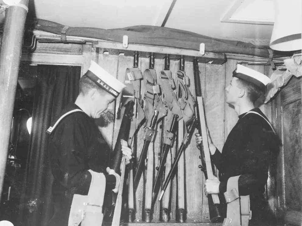 Members of Goorangai’s crew placing rifles on the rack, c. 1939.