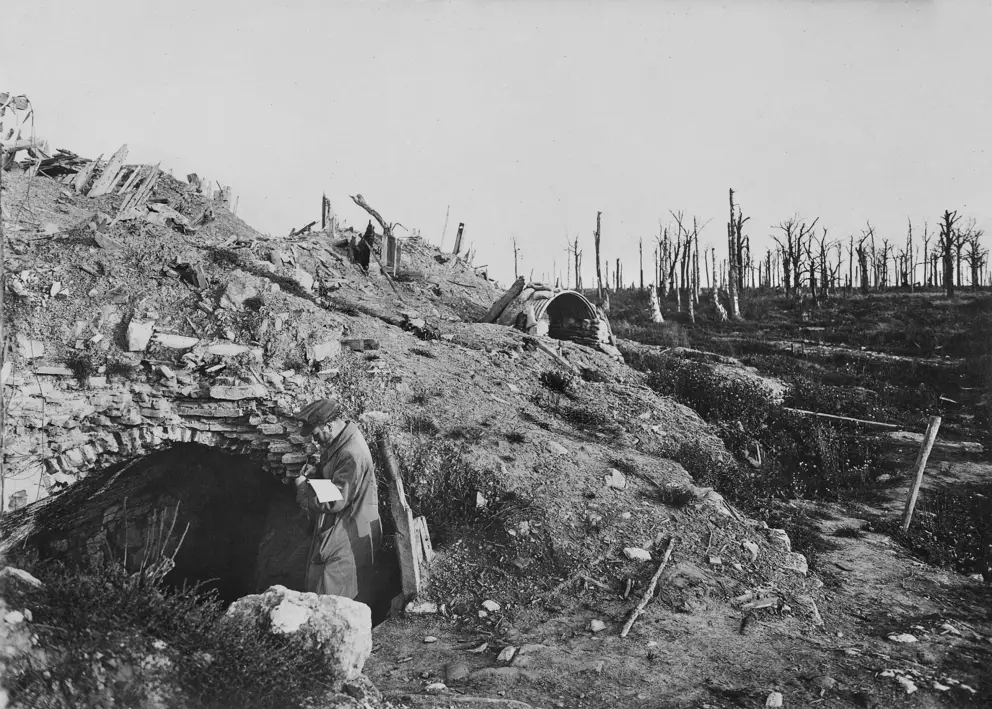Somme, August 1916. A deserted section of the battlefield at Deniécourt with a French soldier inspecting a dugout. H04502