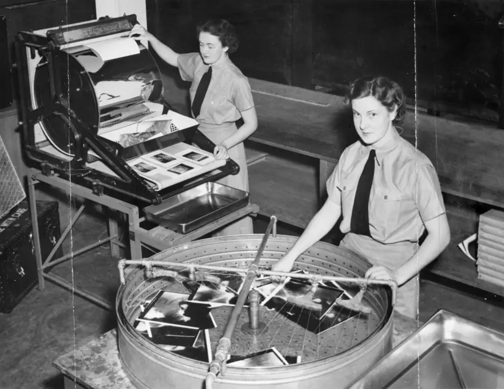 WAAAF officers print and treat photographs in a darkroom.
