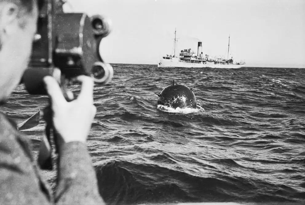 On board the minesweeper HMAS Orara, filming a German mine which has been swept from Bass Strait, 1940